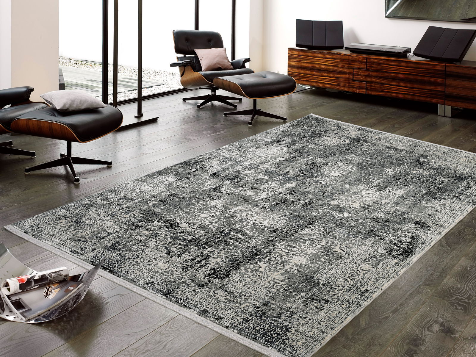 Designer Teppich in modernem Wohnzimmer, aus der Vogelperspektive fotografiert, mit eleganten schwarzen Sesseln und einem Holzmöbel im Hintergrund.