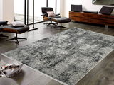 Designer Teppich in modernem Wohnzimmer, aus der Vogelperspektive fotografiert, mit eleganten schwarzen Sesseln und einem Holzmöbel im Hintergrund.
