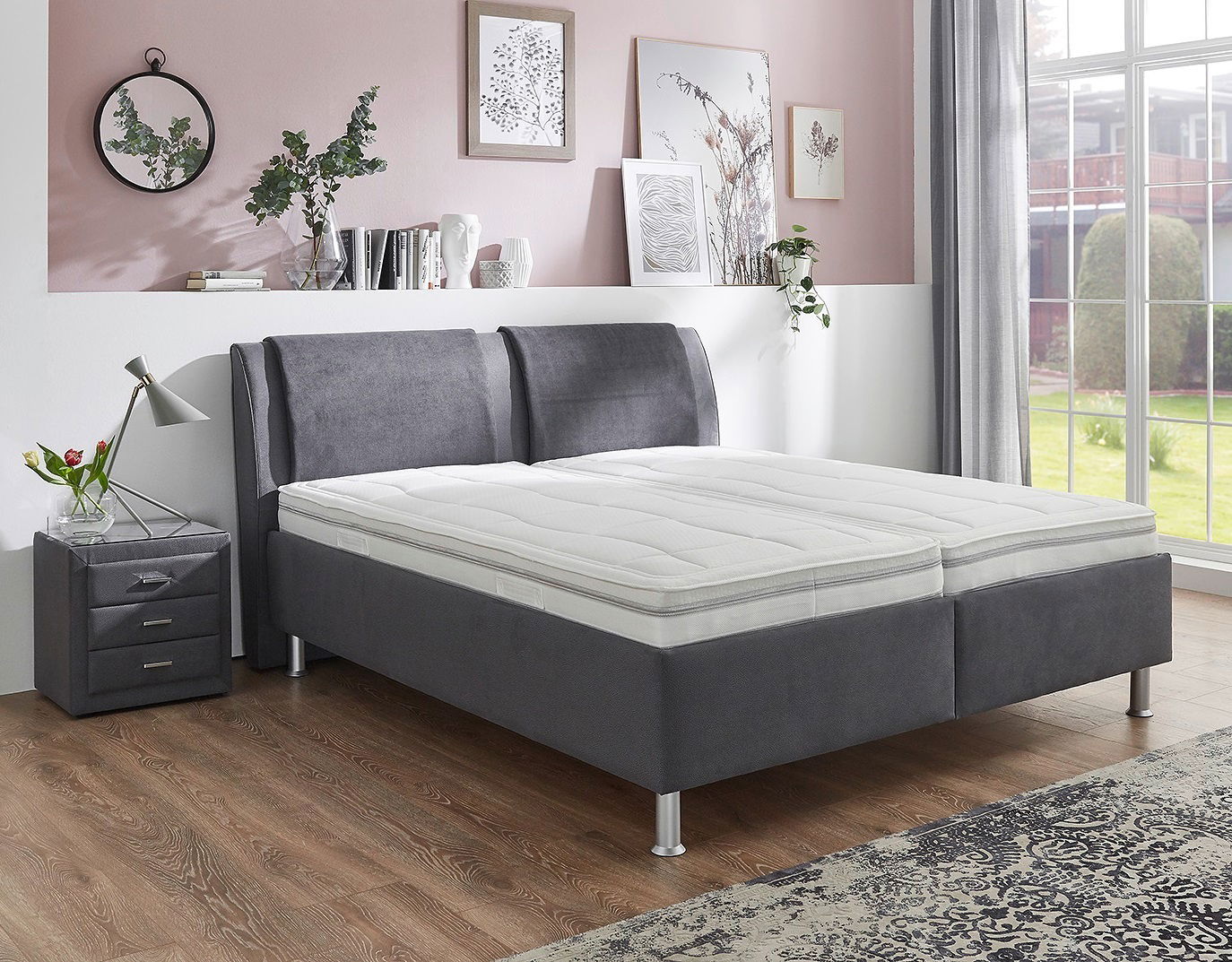 Graues Polsterbett in einem stilvoll eingerichteten Schlafzimmer, seitliche Perspektive