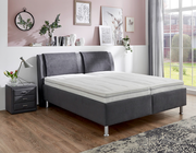 Graues Polsterbett in einem stilvoll eingerichteten Schlafzimmer, seitliche Perspektive