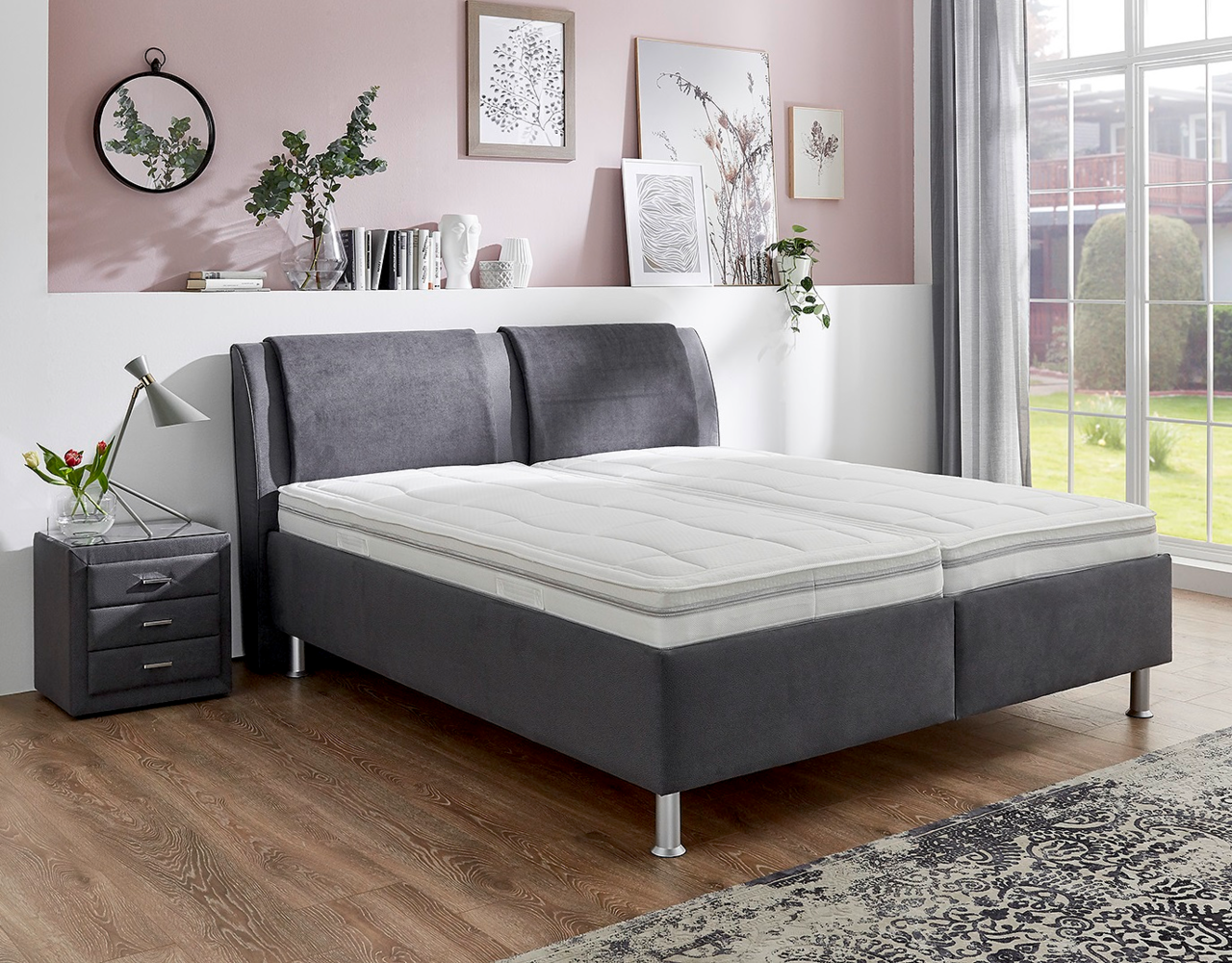 Graues Polsterbett in einem stilvoll eingerichteten Schlafzimmer, seitliche Perspektive