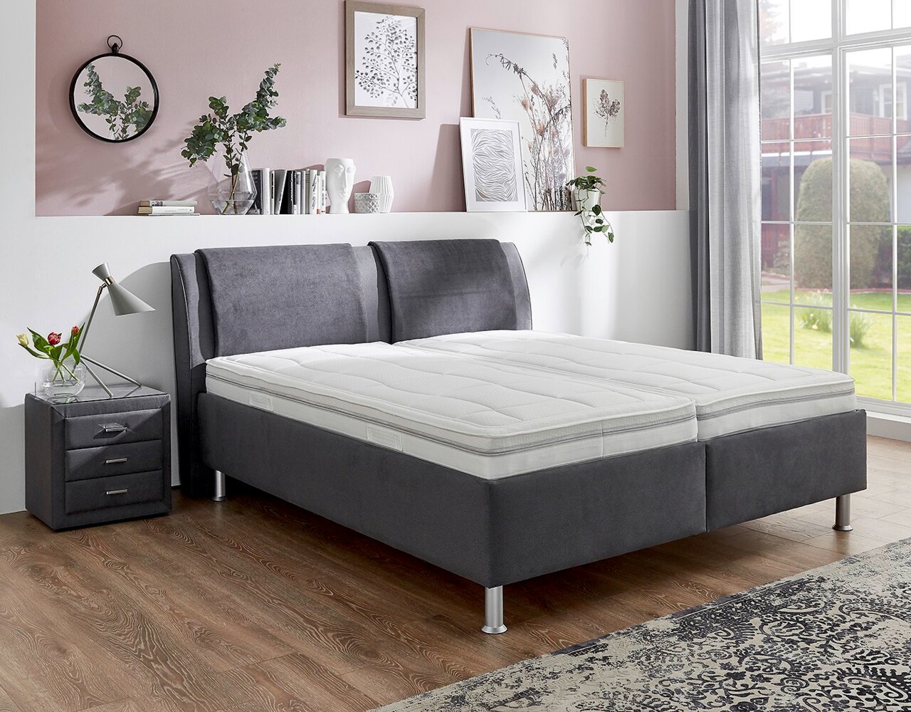 Graues Polsterbett in einem stilvoll eingerichteten Schlafzimmer, seitliche Perspektive