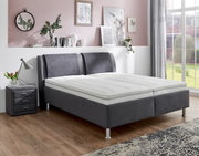 Graues Polsterbett in einem stilvoll eingerichteten Schlafzimmer, seitliche Perspektive
