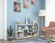 Weißes, modernes Regal/Sideboard mit offenen Fächern und Büchern, dekoriert mit Kerzenhaltern und Pflanzen, im Wohnzimmer vor blauer Wand neben Stehlampe und rosa Sessel; Perspektive: frontale Ansicht auf Augenhöhe.