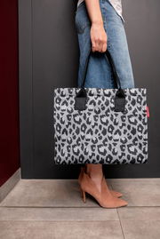 Person hält eine Tasche mit Leopardenmuster in der Hand, seitliche Perspektive
