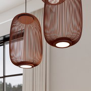 Zwei moderne, ovale Pendelleuchten mit braunem, lamellenartigem Schirm und integriertem LED-Diffusor, in einem hellen Wohnraum; Perspektive: leicht von unten im Nahblick.