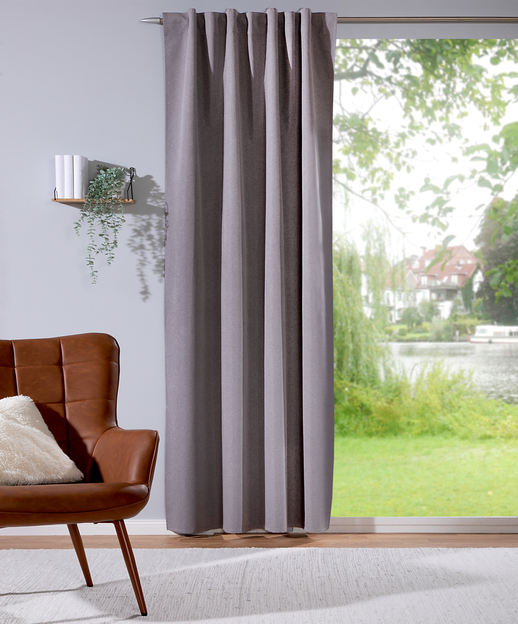 Grauer Verdunklungsvorhang 135x245cm in einem modernen Wohnzimmer, seitliche Perspektive, mit Blick auf einen Garten durch das Fenster.