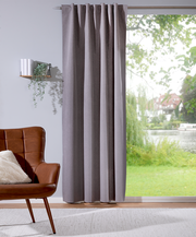 Grauer Verdunklungsvorhang 135x245cm in einem modernen Wohnzimmer, seitliche Perspektive, mit Blick auf einen Garten durch das Fenster.