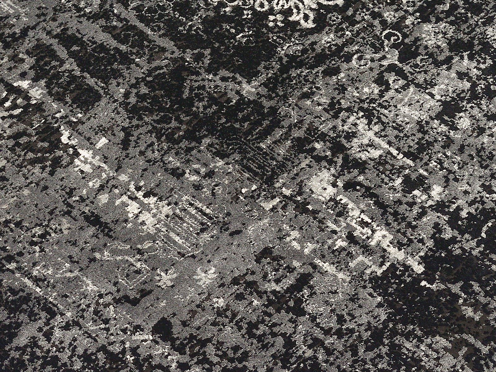 Nahaufnahme eines Designer-Teppichs mit abstraktem, schwarz-grauem Muster in Draufsicht.