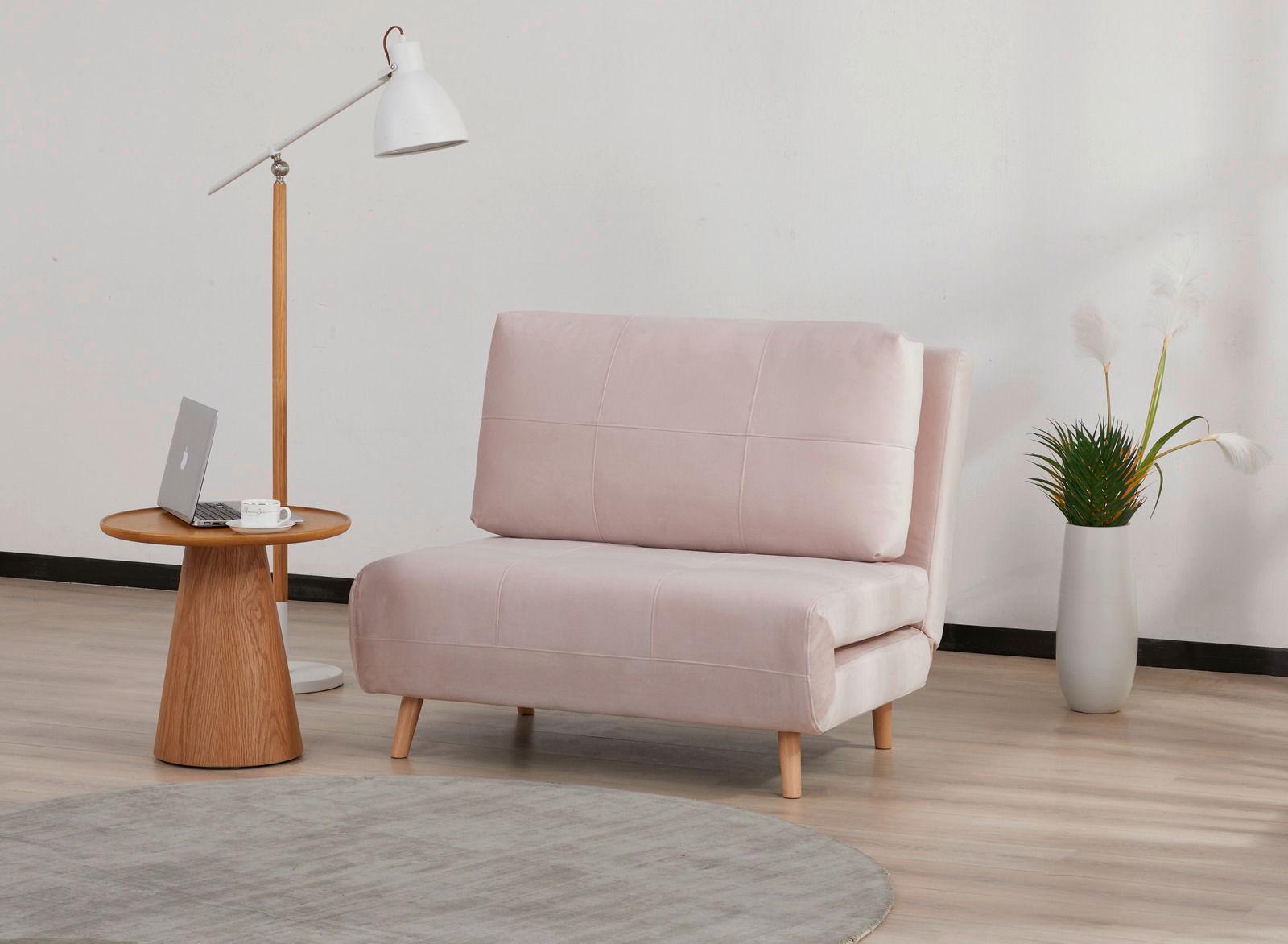 Rosa Funktionssessel in modernem Wohnzimmer, seitliche Perspektive, neben einem runden Holztisch mit Lampe und Laptop.