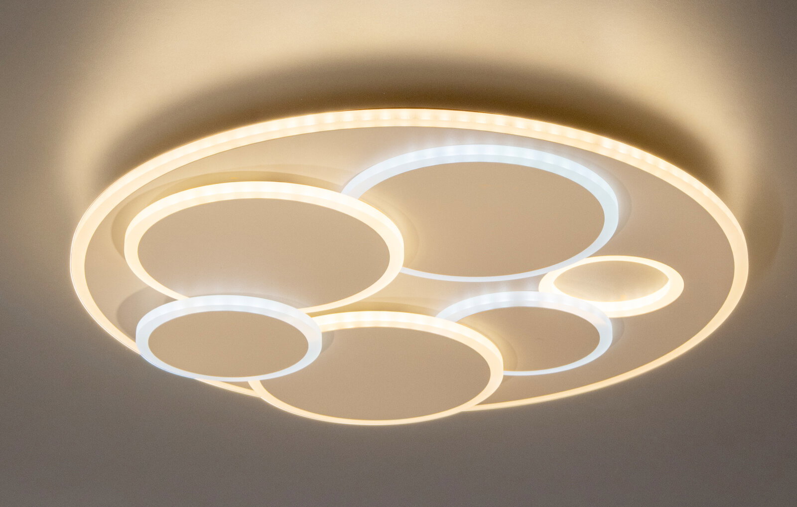 Moderne LED-Deckenleuchte mit mehreren überlappenden Leuchtringen in Warmweiß und Kaltweiß, Ansicht von unten (Untersicht)