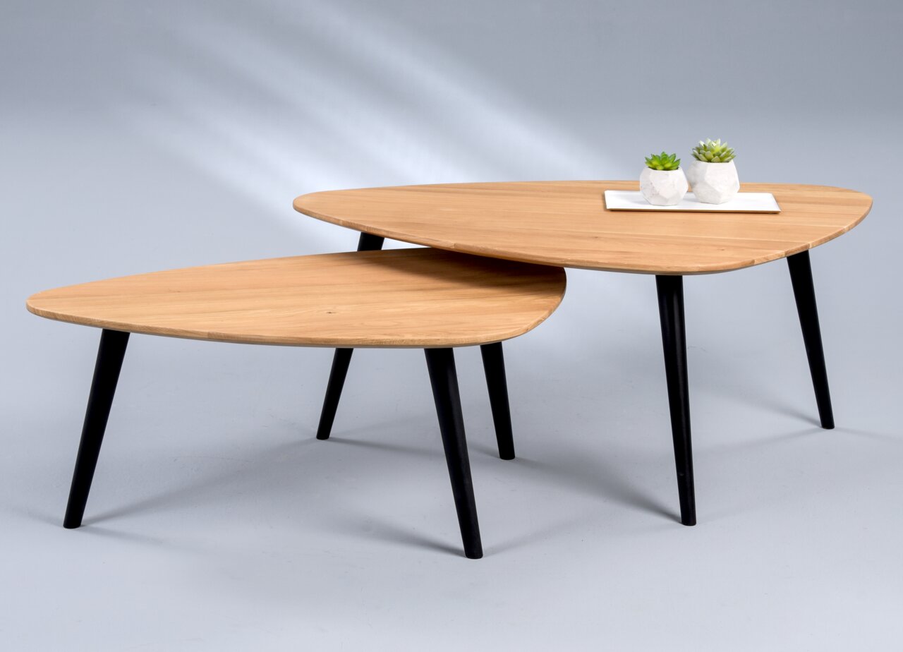 Zwei moderne Couchtische mit dreieckigen Holzplatten und schwarzen Beinen, aus seitlicher Perspektive fotografiert.