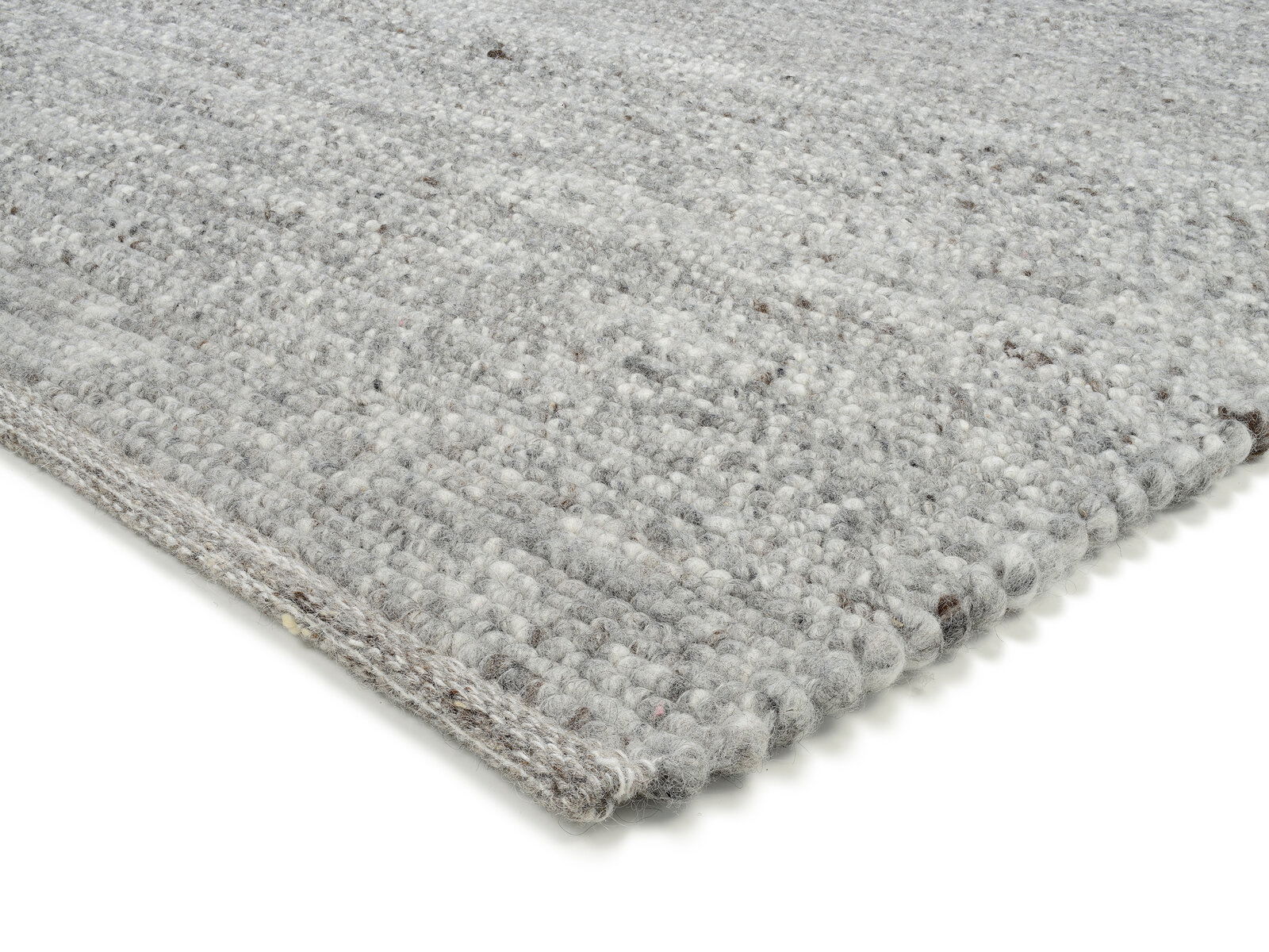 Nahaufnahme eines handgewebten Teppichs in Grautönen, perspektivisch von der Seite aufgenommen.
