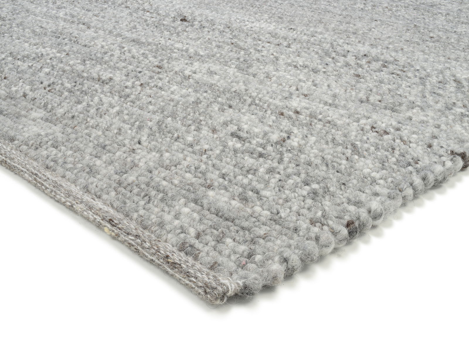 Nahaufnahme eines handgewebten Teppichs in Grautönen, perspektivisch von der Seite aufgenommen.