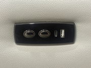 Nahaufnahme eines schwarzen Bedienfelds auf einem hellgrauen Sofa mit zwei Knöpfen und USB-Anschlüssen.