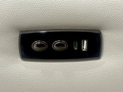 Nahaufnahme eines schwarzen Bedienfelds auf einem hellgrauen Sofa mit zwei Knöpfen und USB-Anschlüssen.