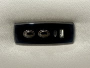Nahaufnahme eines schwarzen Bedienfelds auf einem hellgrauen Sofa mit zwei Knöpfen und USB-Anschlüssen.