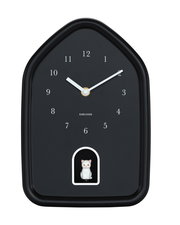 Schwarze Wanduhr in Hausform mit weißen Ziffern und Zeigern, darunter eine kleine weiße Katzenfigur in einer Öffnung. Frontalansicht.