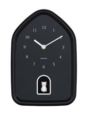 Zwarte wandklok in de vorm van een huisje met witte cijfers en wijzers, met daaronder een klein wit kattenfiguurtje in een uitsparing. Vooraanzicht.