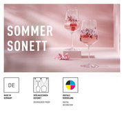 Zwei elegante Sprizzgläser mit floraler Verzierung, gefüllt mit einem sommerlichen Getränk und Beeren, auf einem rosa Hintergrund. Seitliche Perspektive.