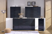Moderne Hochkommode in dunklem Hochglanz-Finish, frontal fotografiert, umgeben von stilvoller Dekoration.