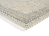 Designer Teppich in Beige- und Grautönen mit Fransen, perspektivisch von der Ecke aufgenommen