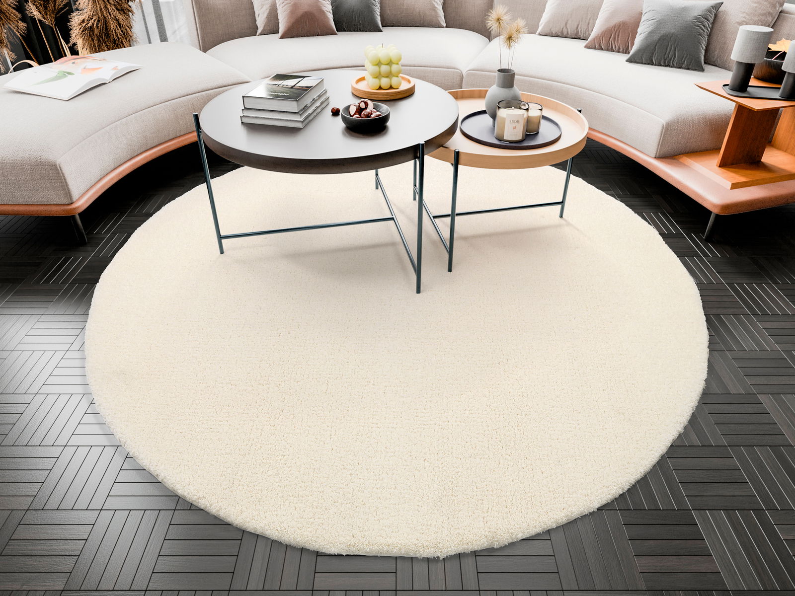 Runder, cremefarbener Teppich Soft Dream mit einem Durchmesser von ca. 120 cm, platziert in einem modernen Wohnzimmer mit dunklem Holzboden und einem Sofa im Hintergrund, aus der Vogelperspektive betrachtet.