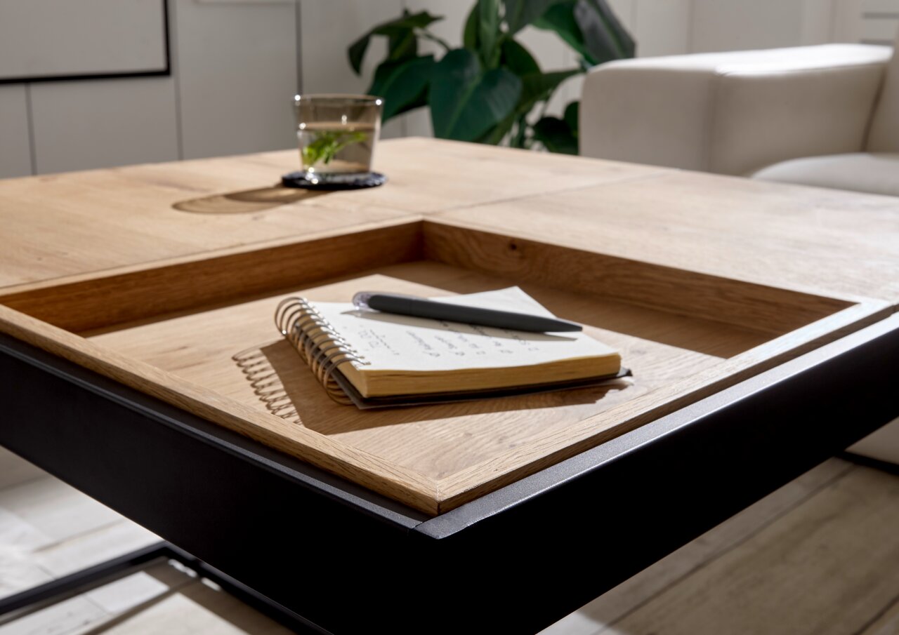 Moderner Couchtisch aus Holz und Metall mit eingelassener Ablage, Notizbuch und Stift darauf, seitliche Perspektive.
