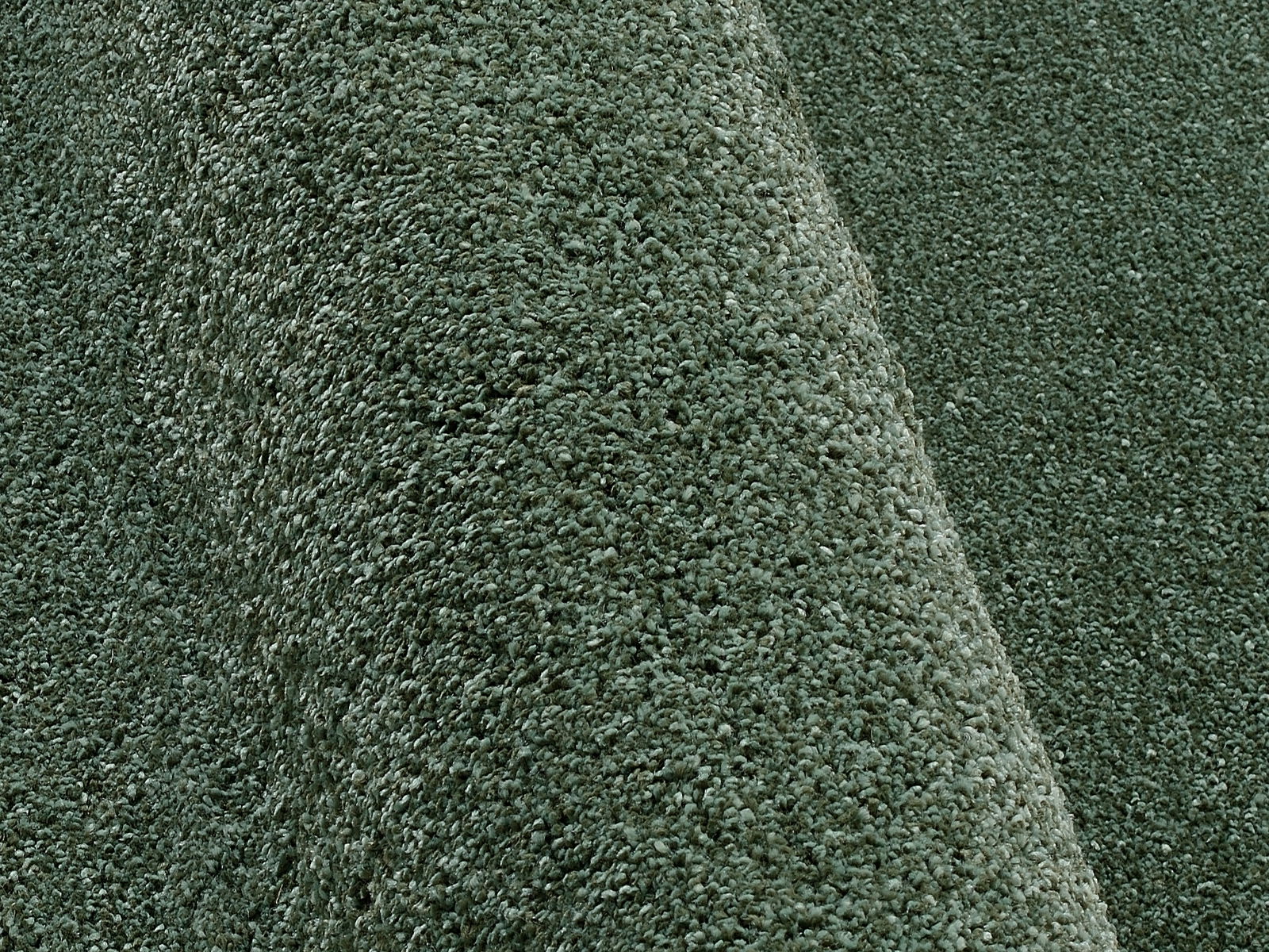 Nahaufnahme eines grünen Uni-Teppichs mit weicher Textur, seitliche Perspektive