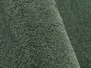 Nahaufnahme eines grünen Uni-Teppichs mit weicher Textur, seitliche Perspektive