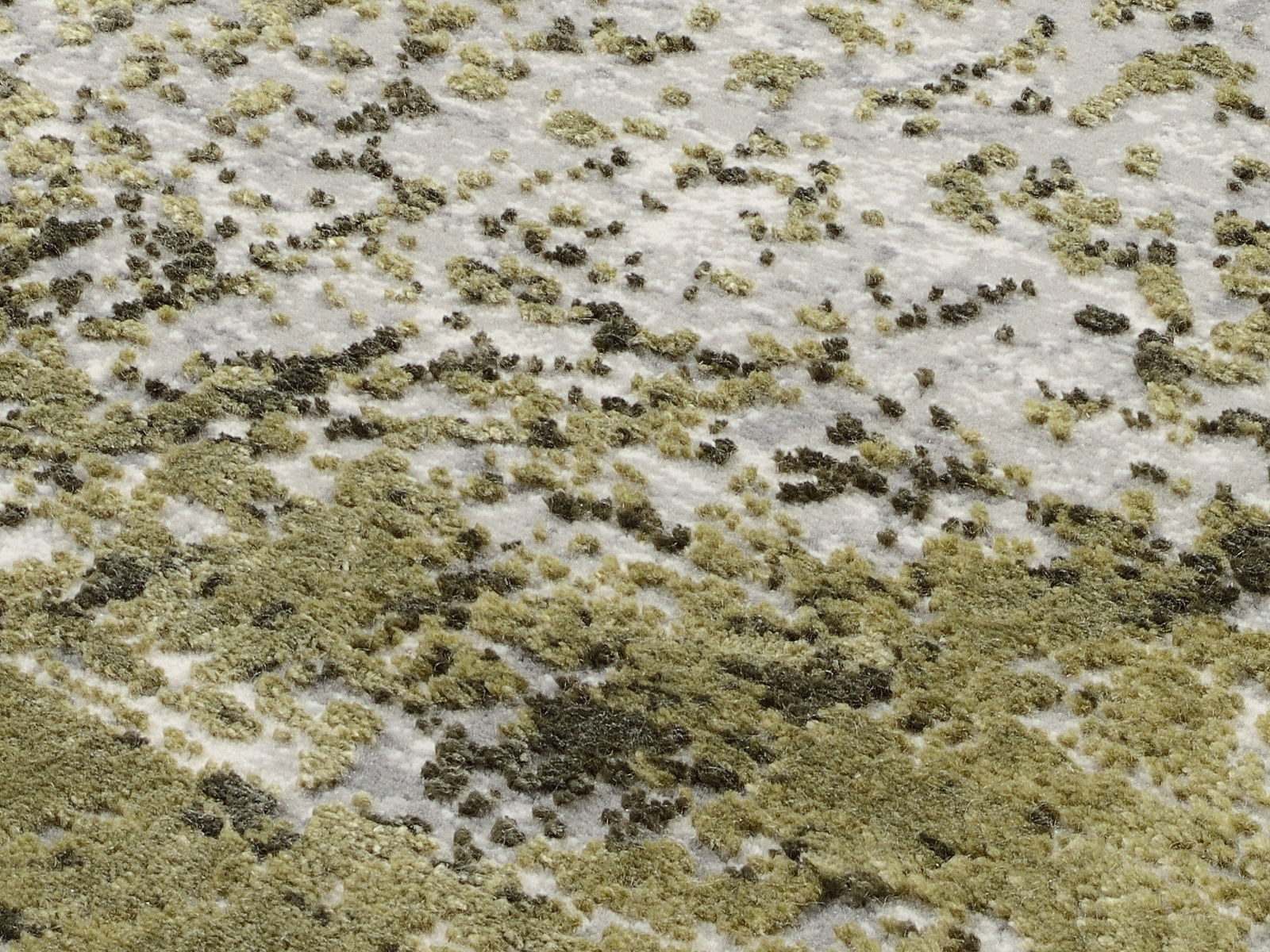 Nahaufnahme eines Designer-Teppichs mit grünem und weißem Muster, aus schräger Perspektive fotografiert.