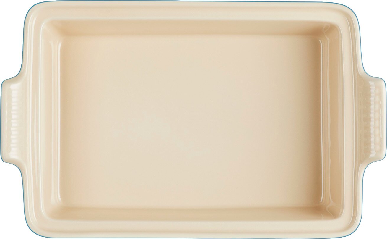 Beige rechthoekige ovenschaal van keramiek met handgrepen aan beide kanten, bovenaanzicht op witte achtergrond