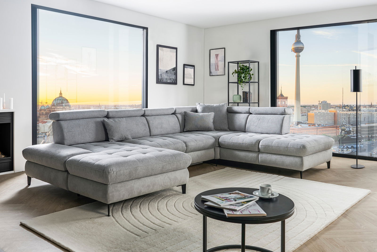 Graue Rundecke (L) in modernem Wohnzimmer mit Blick auf die Stadt, seitliche Perspektive