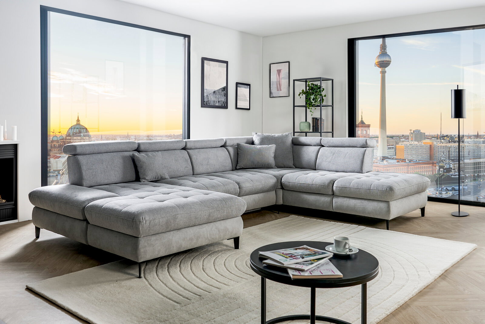 Graue Rundecke (L) in modernem Wohnzimmer mit Blick auf die Stadt, seitliche Perspektive