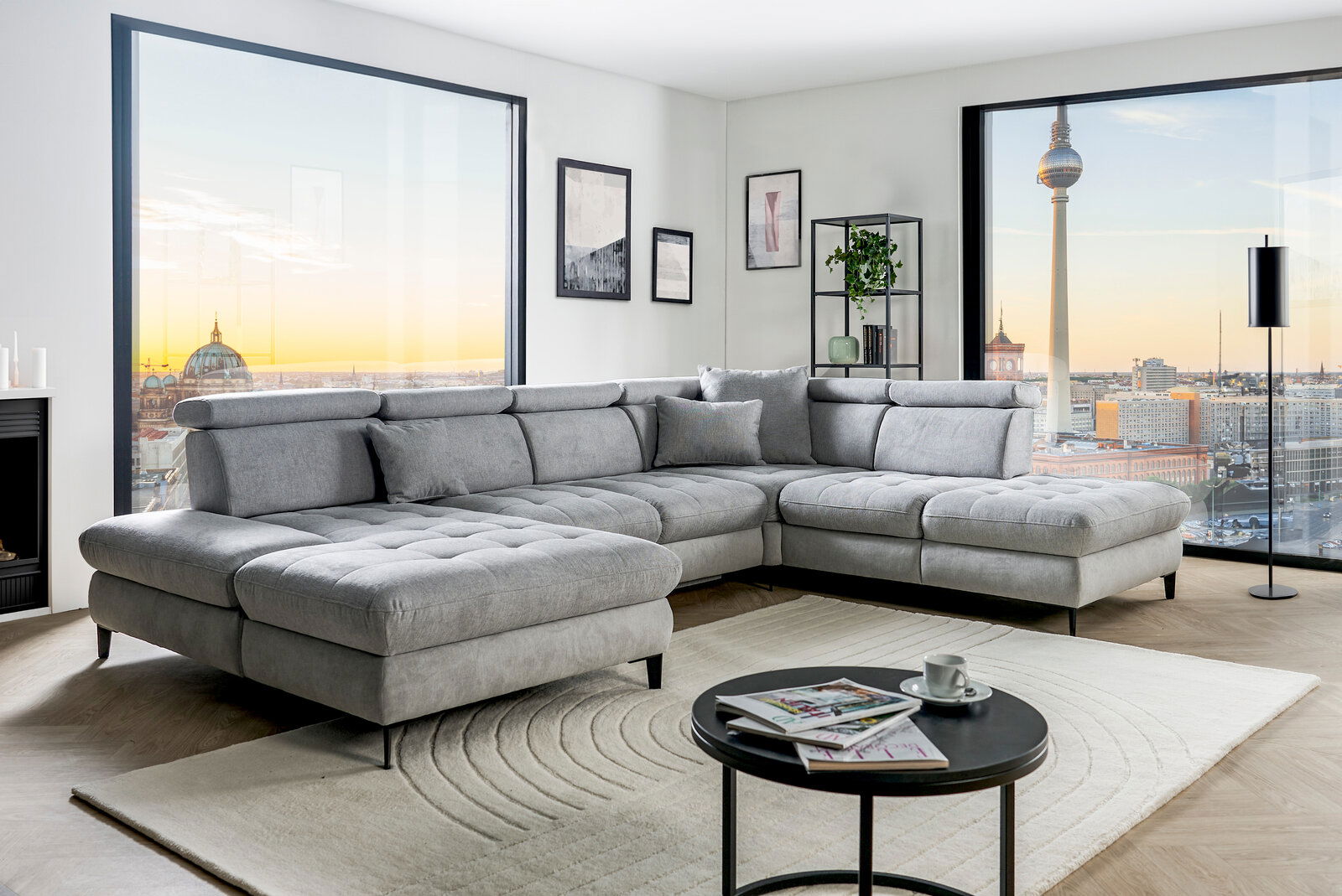 Graue Rundecke (L) in modernem Wohnzimmer mit Blick auf die Stadt, seitliche Perspektive
