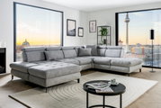 Graue Rundecke (L) in modernem Wohnzimmer mit Blick auf die Stadt, seitliche Perspektive
