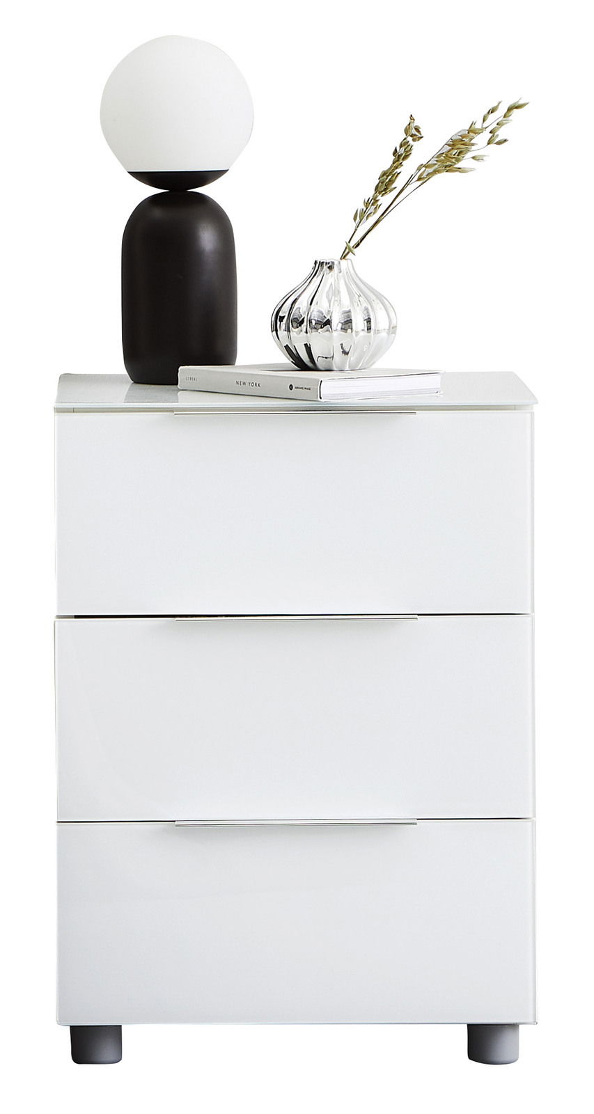 Weiße Nachtkonsole mit drei Schubladen, darauf eine moderne Lampe und eine dekorative Vase, Frontalansicht