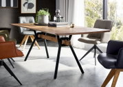 Moderne rechthoekige houten eettafel met zwart metalen A-poten in een lichte eetkamer, schuin van voren gefotografeerd met stoelen eromheen