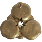 Goldenes Wandornament mit organischer Form und sternförmiger Öffnung in der Mitte, aus der Vorderansicht betrachtet.