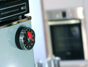 Mechanischer Küchentimer in Nahaufnahme, seitlich an einem Gerät befestigt, mit rotem und schwarzem Ziffernblatt.