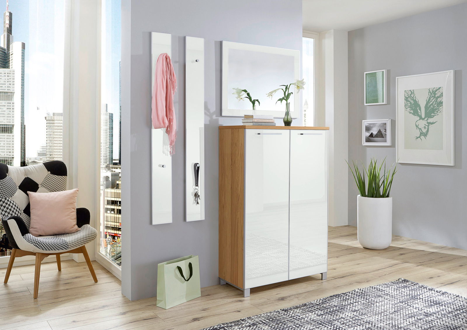 VOSS Garderoben-Set 4-tlg. SANTINA Modernes Garderoben-Set in einem hellen Raum mit Stadtblick, bestehend aus einem Schrank mit Holz- und weißen Elementen, zwei schmalen Wandpaneelen mit Haken und einem Spiegel. Perspektive von vorne.