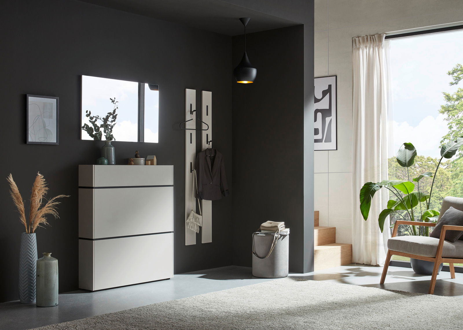 Voleo Garderobenpaneel UNIQUE Moderner Eingangsbereich mit einem weißen Schuhschrank, einem rechteckigen Spiegel und einem Garderobenpaneel an einer dunklen Wand. Perspektive von vorne.