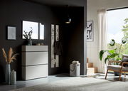 Moderner Eingangsbereich mit einem weißen Schuhschrank, einem rechteckigen Spiegel und einem Garderobenpaneel an einer dunklen Wand. Perspektive von vorne.