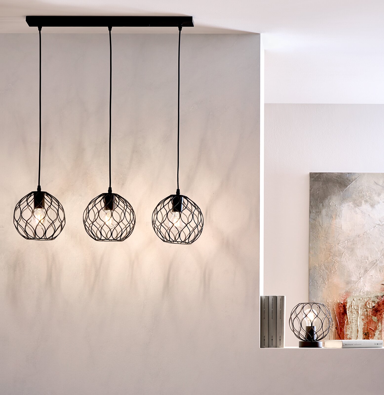 Marama Hanglamp Drei moderne Hängeleuchten mit schwarzen, geometrischen Drahtschirmen, von der Decke hängend, in einem stilvollen Raum. Seitliche Perspektive.