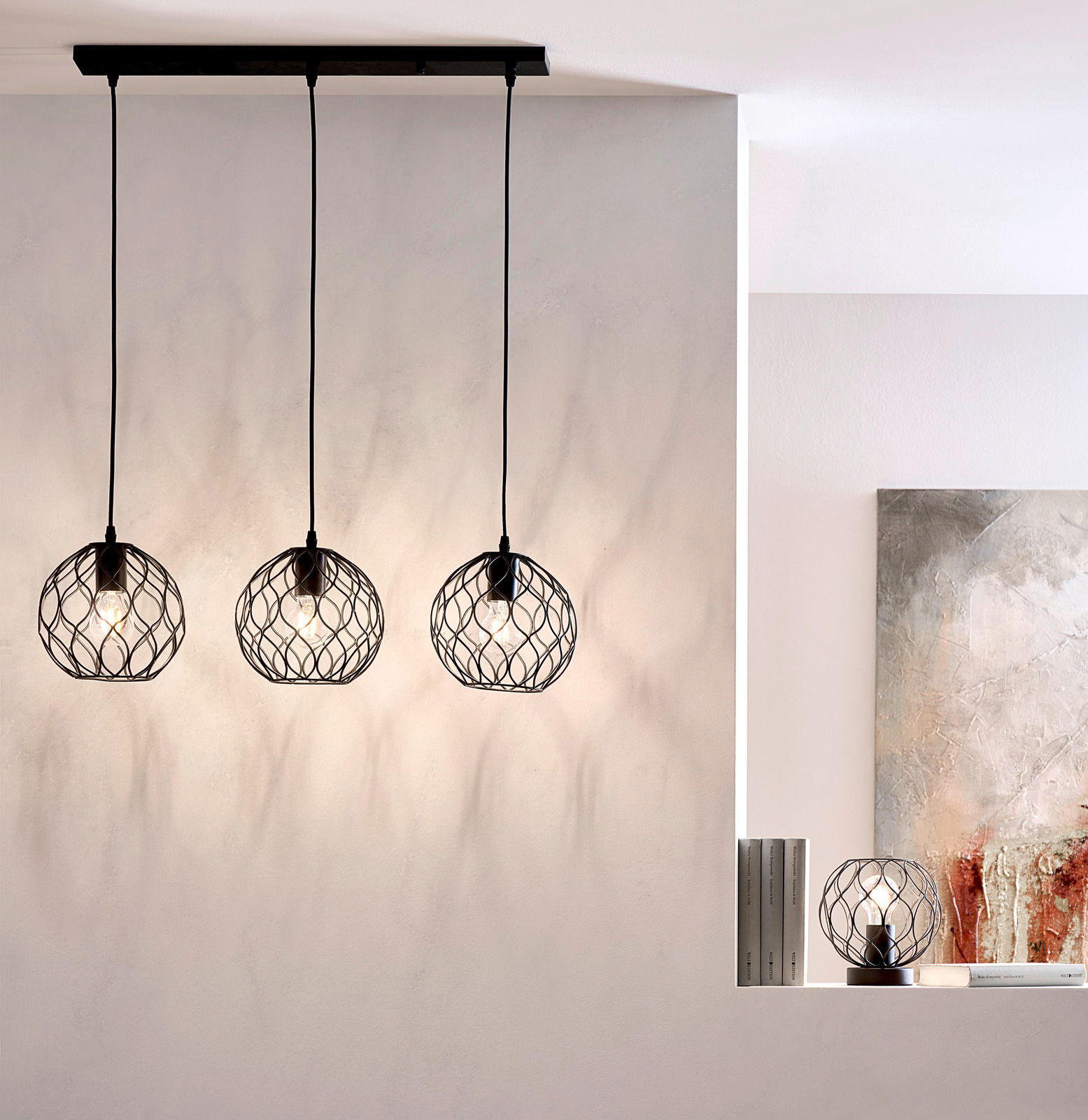 Drei moderne Hängeleuchten mit schwarzen, geometrischen Drahtschirmen, von der Decke hängend, in einem stilvollen Raum. Seitliche Perspektive.