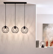 Drei moderne Hängeleuchten mit schwarzen, geometrischen Drahtschirmen, von der Decke hängend, in einem stilvollen Raum. Seitliche Perspektive.