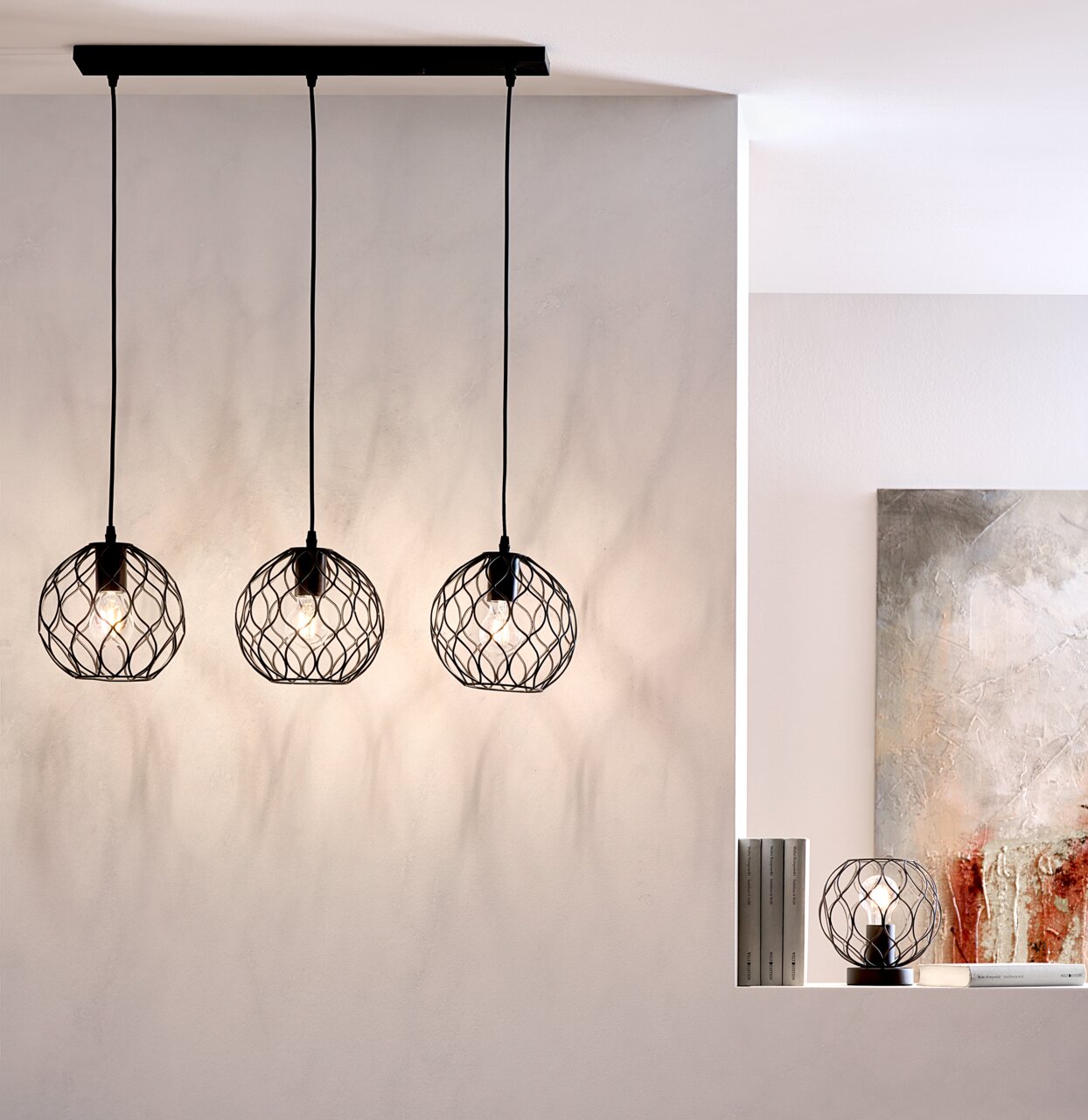 Drei moderne Hängeleuchten mit schwarzen, geometrischen Drahtschirmen, von der Decke hängend, in einem stilvollen Raum. Seitliche Perspektive.