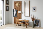 Holzgarderobenpaneel mit Haken, an dem Kleidung und Accessoires hängen, daneben ein Spiegel und eine Bank mit Schuhen, aus seitlicher Perspektive fotografiert.