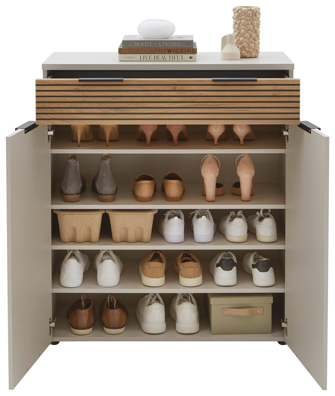 Schuhschrank mit offenen Türen, gefüllt mit verschiedenen Schuhen, von vorne gesehen. Obenauf stehen Dekorationsgegenstände und Bücher.