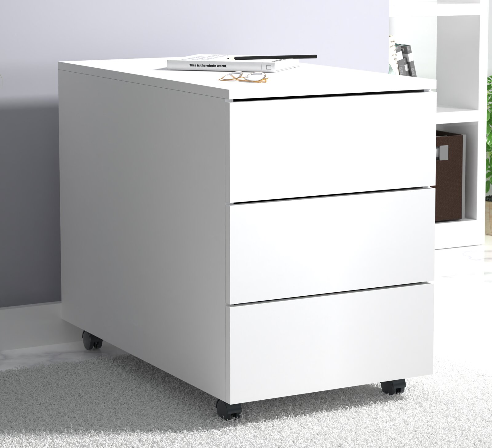 Weißer Rollcontainer mit drei Schubladen, Seitenansicht schräg von vorn (linke Frontperspektive), auf Rollen im modernen Büro.